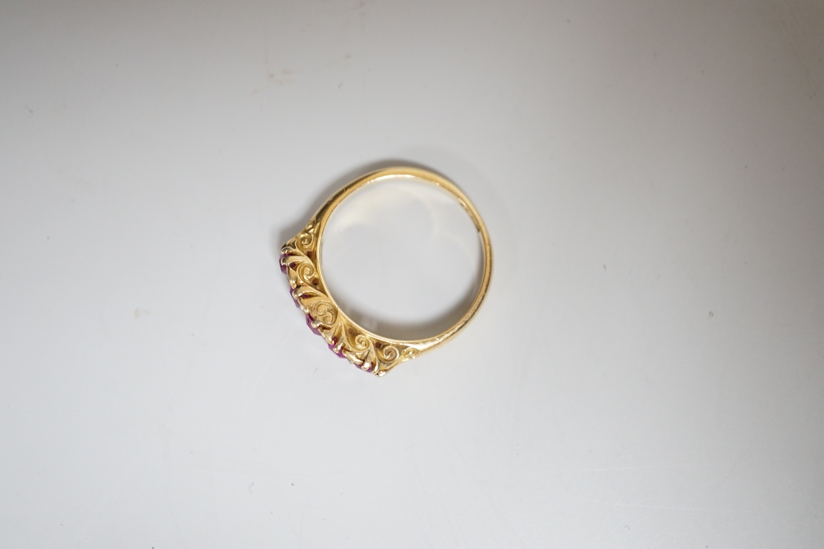 An early to mid 20th century 18ct and graduated five stone ruby set half hoop ring, with diamond chip spacers, size L, gross weight 3.5 grams.